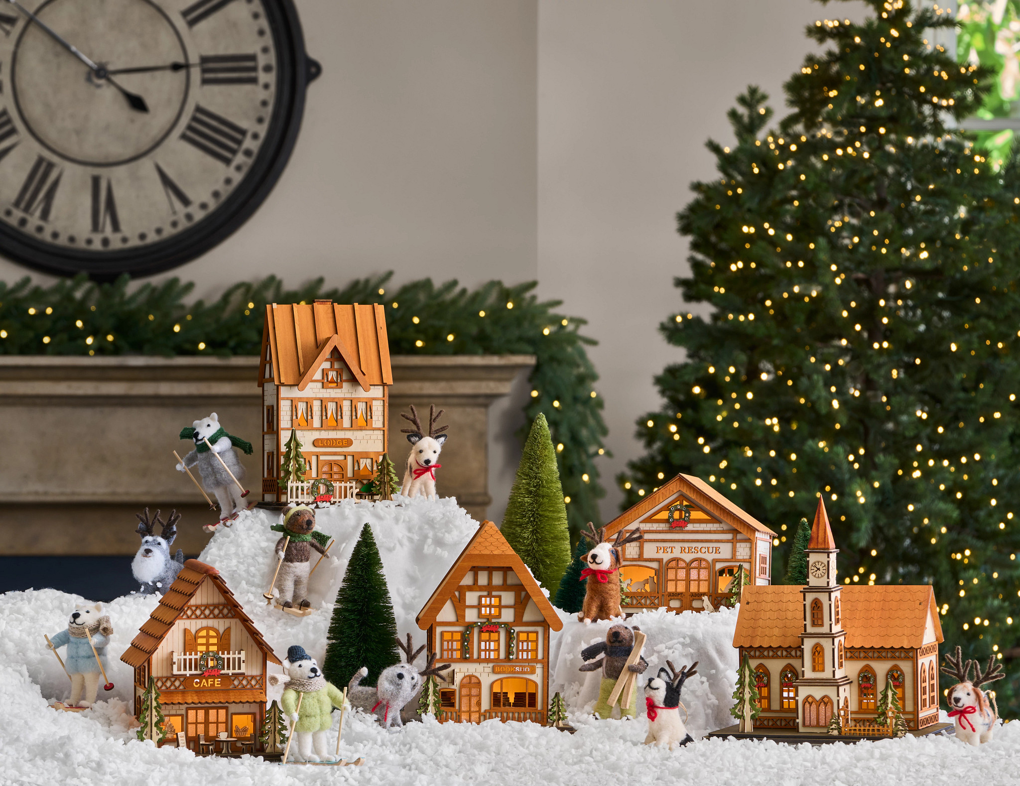  Miniature Christmas village and animal felt ornaments displayed on artificial snow