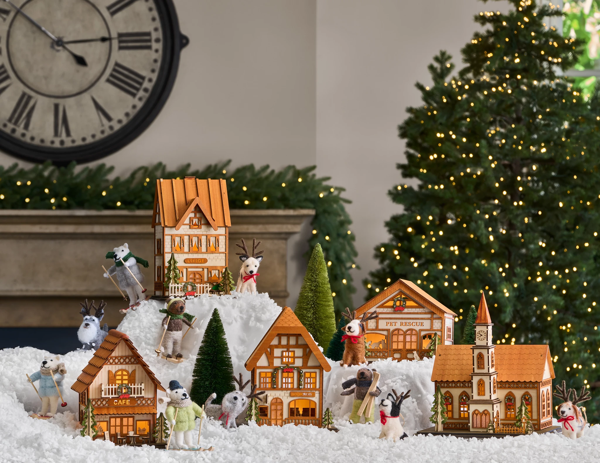 Miniature Christmas village and animal felt ornaments displayed on artificial snow