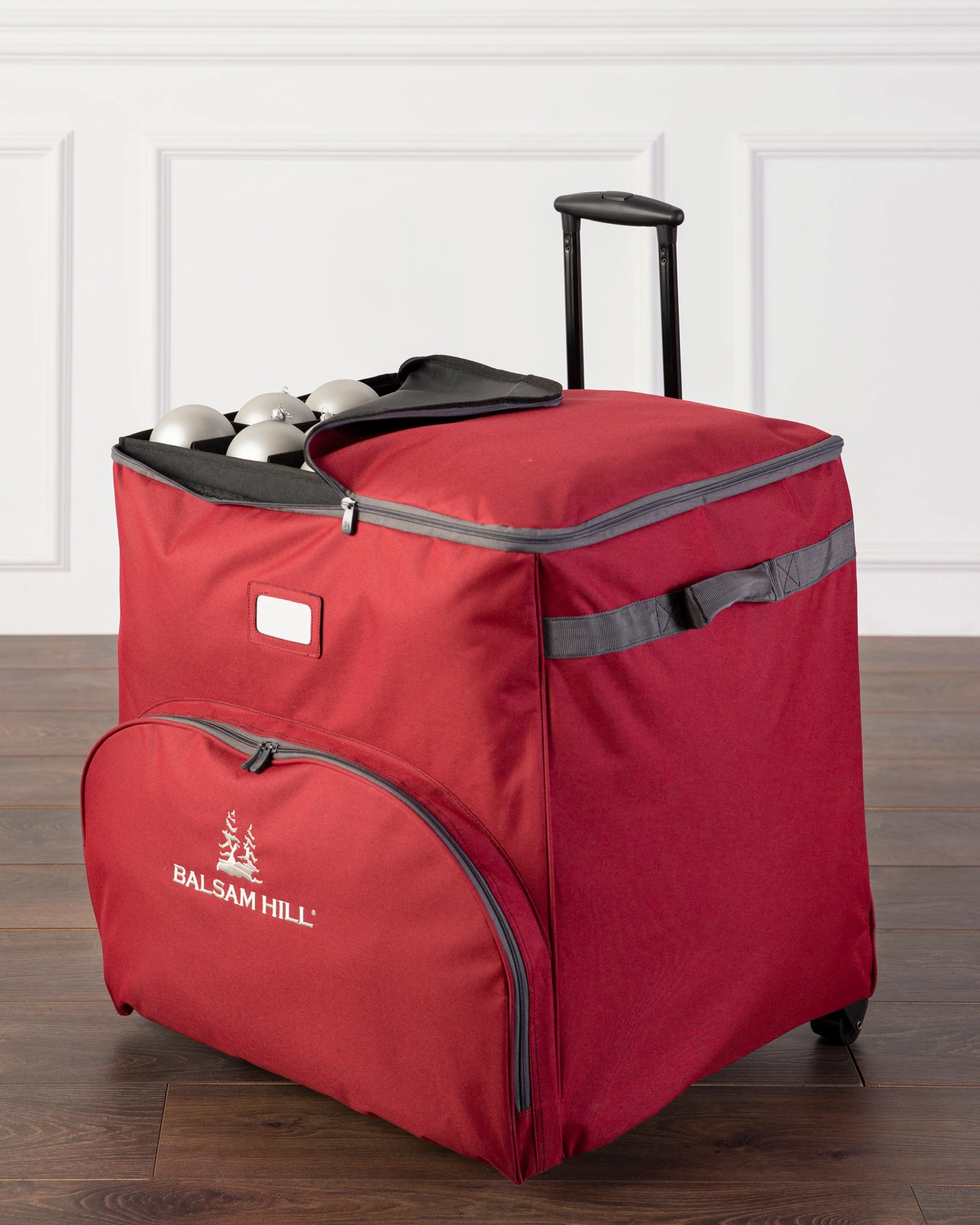 A red rolling suitcase with a retractable handle, positioned upright on a flat surface
