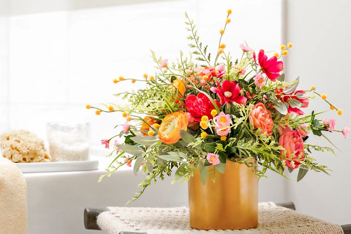 Artificial flower arrangement in a gold vase