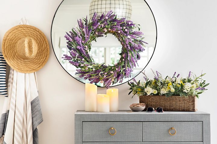 Console table with lavender wreath, flameless candles, and flowers in a basket