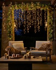 Outdoor patio seating area decorated with string lights, Christmas greenery, and candles