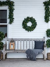 Porch with white siding decorated with Christmas greenery
