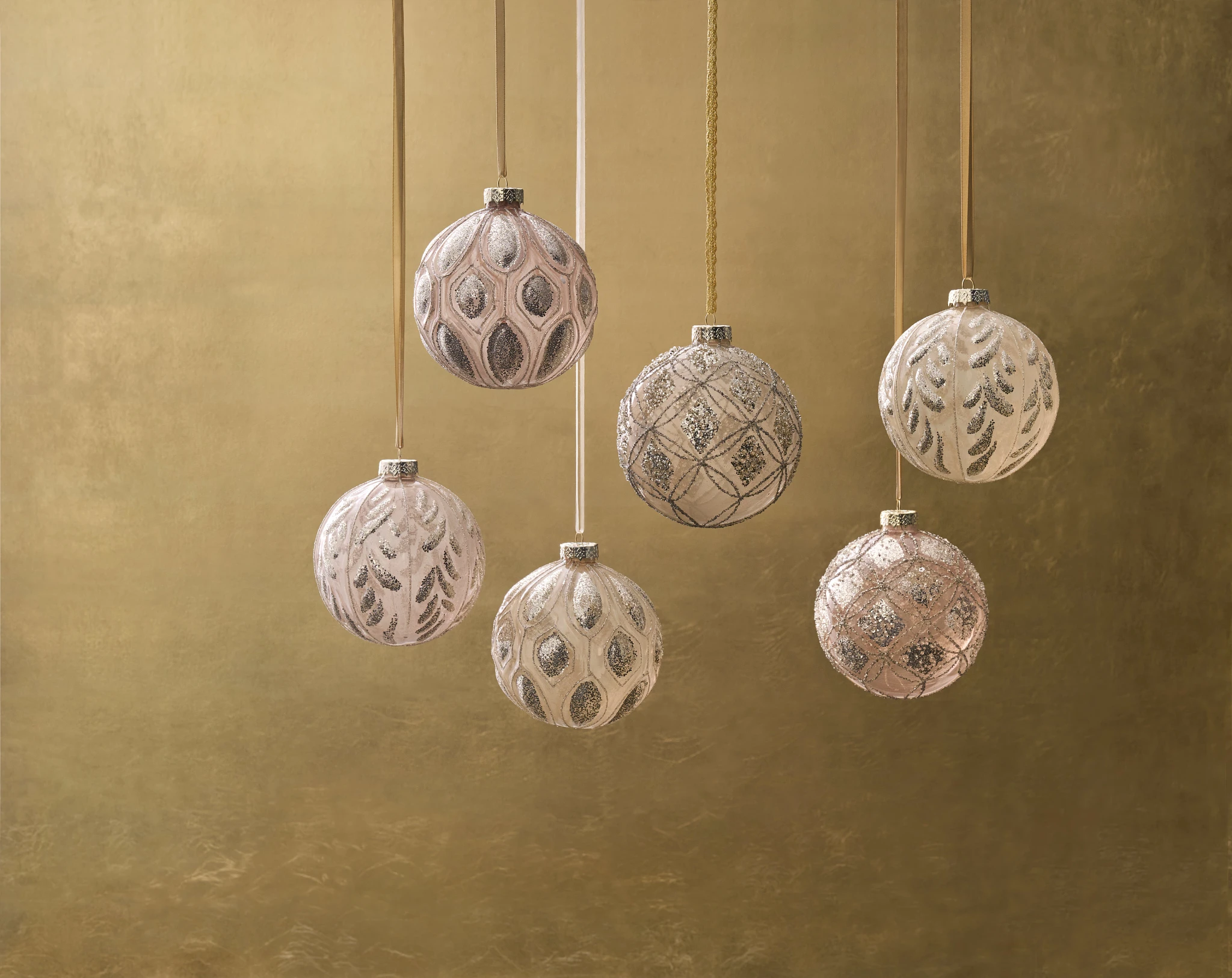 Jumbo blush gold Christmas balls hanging on gold ribbon against gold background