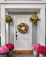 Front porch decorated with wreaths, hanging baskets, and pot fillers