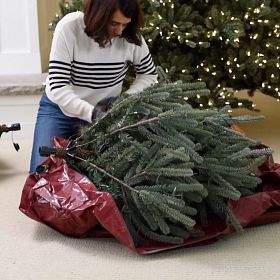 Woman storing section of artificial Christmas tree in storage bag