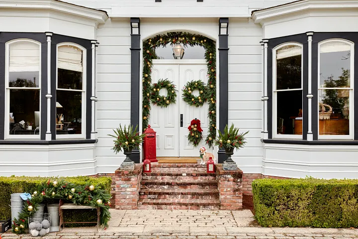 White home façade decorated with Christmas greenery