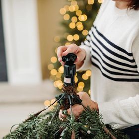 Woman covering the pole connection of an artificial Christmas tree with plastic cap