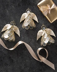 Three angel capiz Christmas ornaments on a gray background