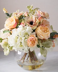 Artificial flower arrangement with hydrangeas, anemone, and roses in clear glass vase