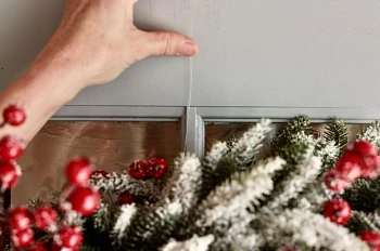 Hand hanging artificial Christmas wreath on door using nylon