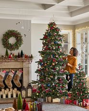 Woman decorating a Christmas tree with colorful ornaments