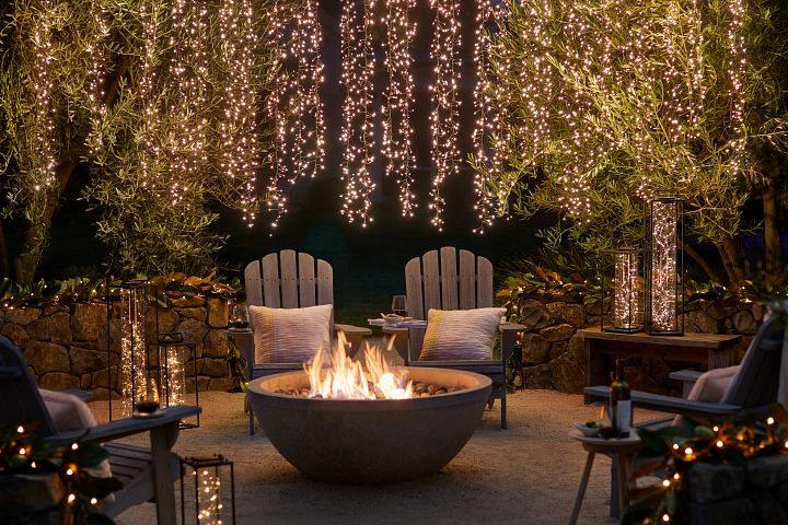 Outdoor seating area with firepit decorated with lights and lanterns