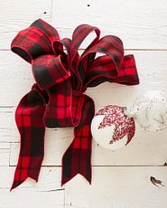 Plaid red ribbon next to white and red ornaments