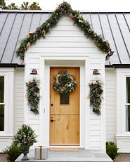 Wide home with wooden door decorated with Christmas greenery