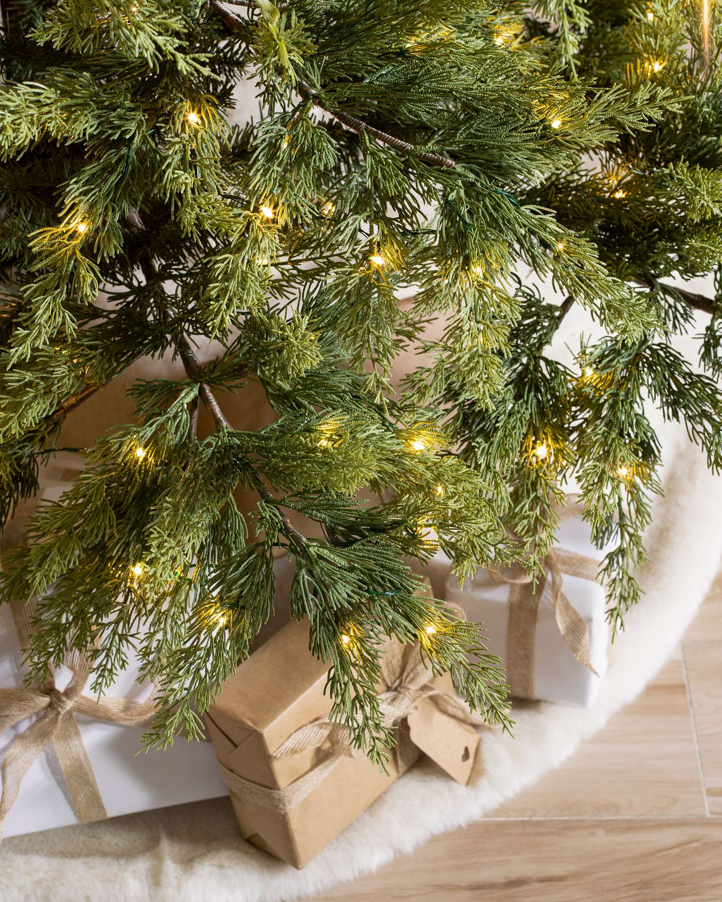 Balsam Hill Grand Canyon Cedar Artificial Christmas Tree LED Clear Closeup with Christmas Skirt and Gift Boxes