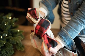 Hands tying plaid and burlap ribbon together