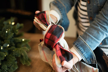 Hands forming two layers of Christmas tree ribbons into a bow