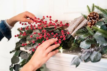 Woman arranging berries on artificial Christmas garland