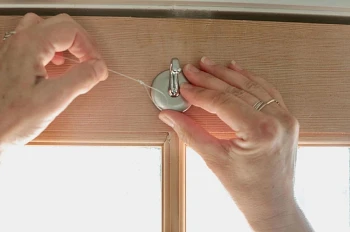 Woman’s hands sticking adhesive hook on top of door