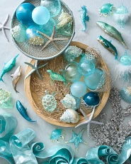 Blue Christmas balls, silver starfish ornaments, and whale ornaments in baskets