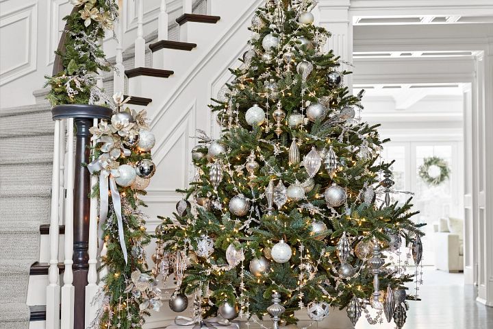 Artificial Christmas tree by the stairs decorated with white and silver ornaments