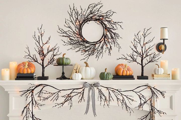 White mantel decorated with candles, pumpkins, and twig wreath and garland