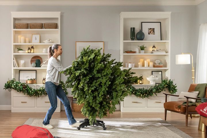 Woman in living room setting up a Balsam Hill Flip Tree
