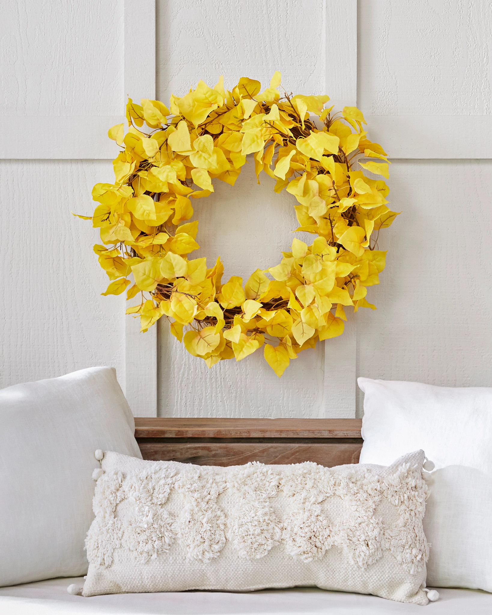 Yellow wreath hanging over a headboard and pillows