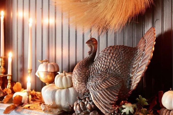 Mantel decorated with bronzed turkey, pumpkins, candles, and autumn leaves