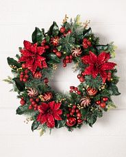 Artificial Christmas wreath decorated with faux poinsettia flowers, berries, and shatter-resistant ball ornaments