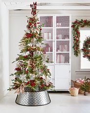 Artificial Christmas tree decorated with red and white ornaments, burlap ribbon, and silver metal bucket collar