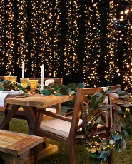 Wooden dining table and chair decorated with string lights and flameless candles